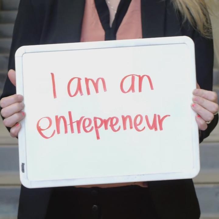 A student holding a sign that says I am an entrepreneur