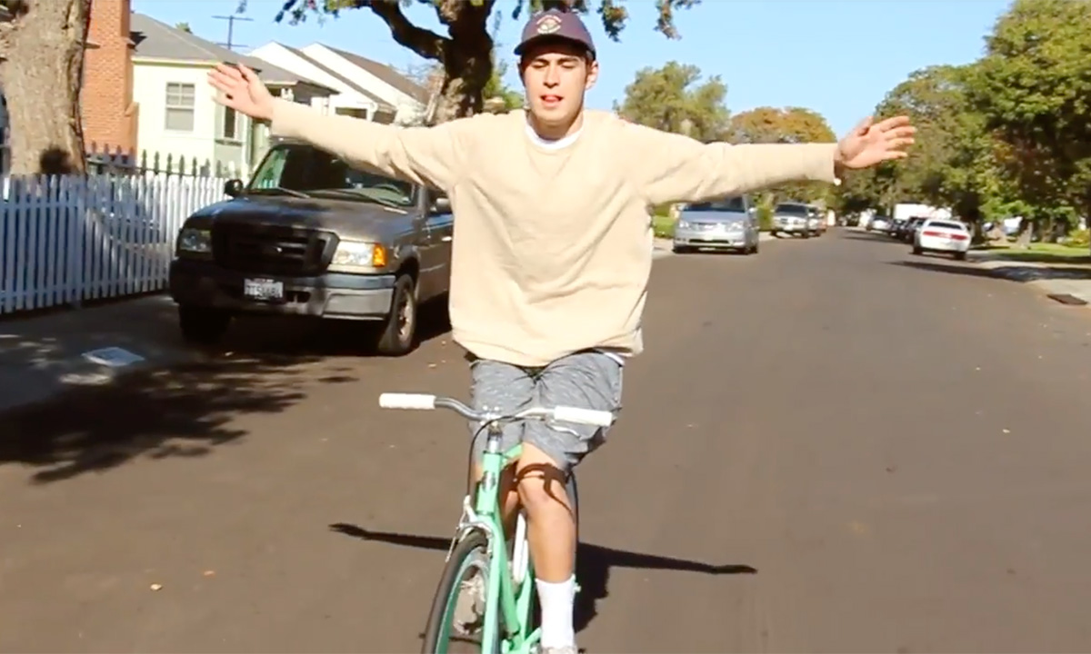 A student riding a bike with his hands outstretched