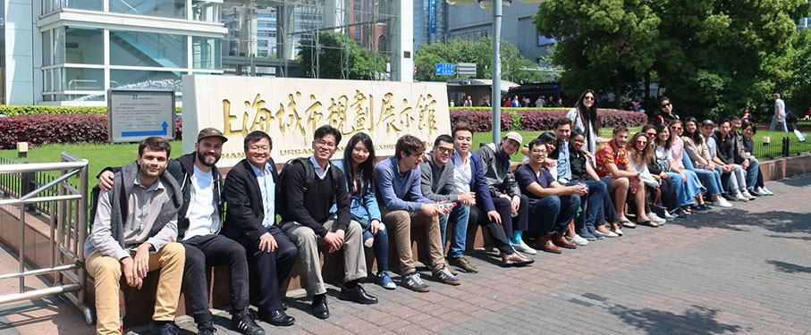 A group of students sitting outside a large building in a foreign country