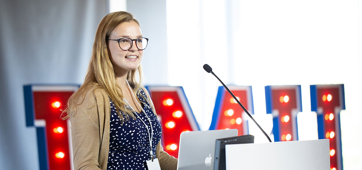 A student giving a large presentation in front of a lecture hall